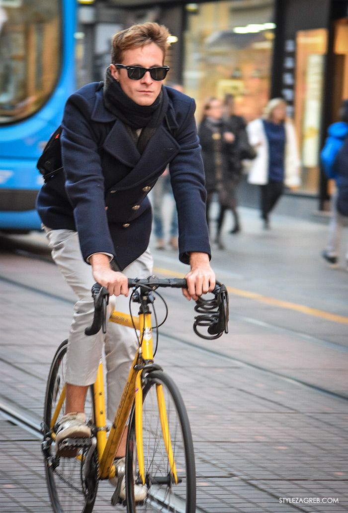 Street Style Zagreb muška moda navy peacoat mornarska jakna muškarac na Ilici u plavom mornarskom kaputiću sa crnim sunčanim naočalama na žutom biciklu street style